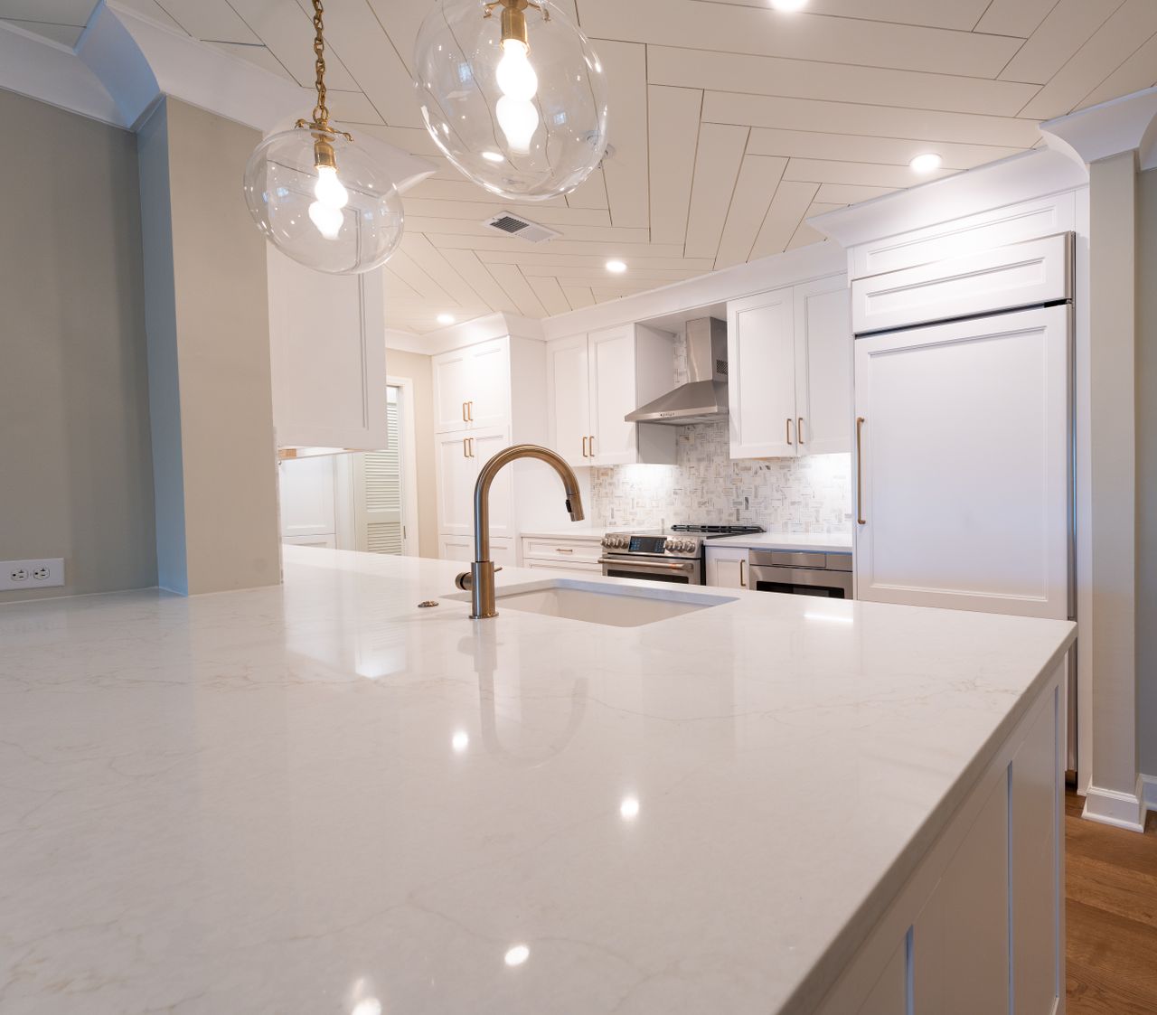 Sleek modern kitchen featuring white cabinets, marble island, and pendant lighting.